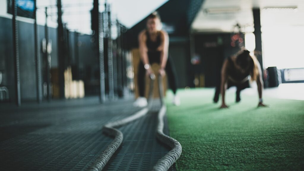 Atletas entrenando con cuerdas de batalla y burpees en un box de CrossFit