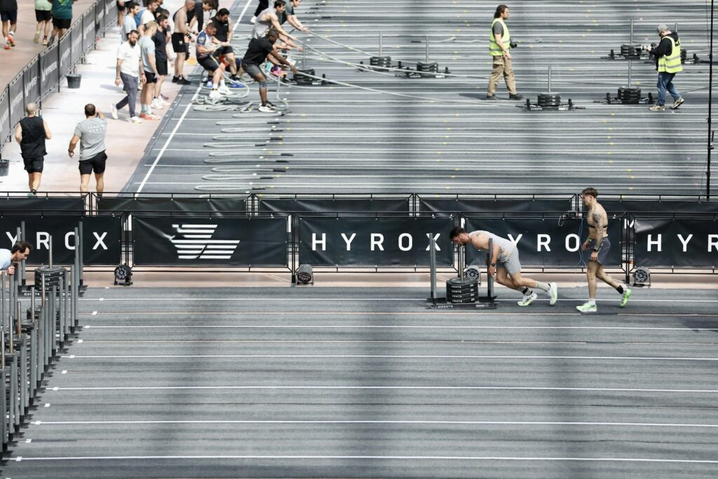 Atletas compitiendo en una carrera Hyrox dentro de un pabellón